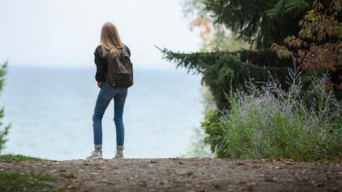 Beautiful girl with backpack on the coast Stock Photo
