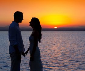 Couple standing by the lake at sunrise Stock Photo