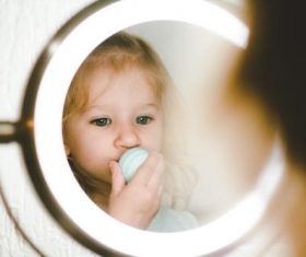 Cute blond little girl looking in the mirror Stock Photo 01