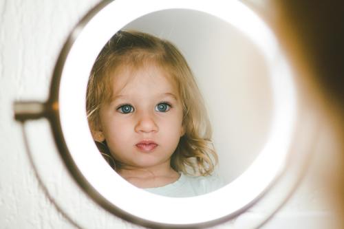 Cute blond little girl looking in the mirror Stock Photo 02