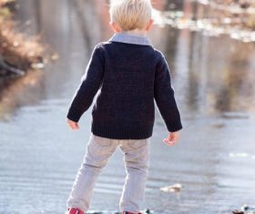Little boy looking at the fallen leaves in the river Stock Photo