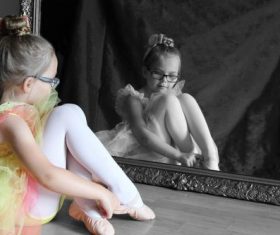 Little girl sitting in front of the mirror wearing dance shoes Stock Photo