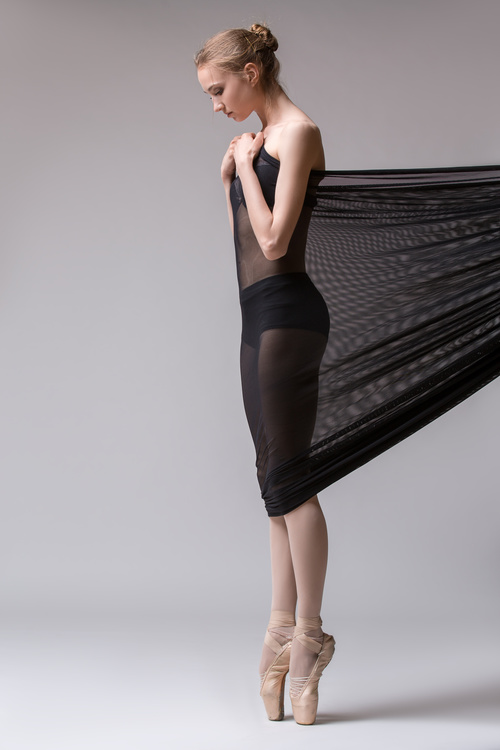 Slim dancer plays with black mesh fabric in the studio Stock Photo 02