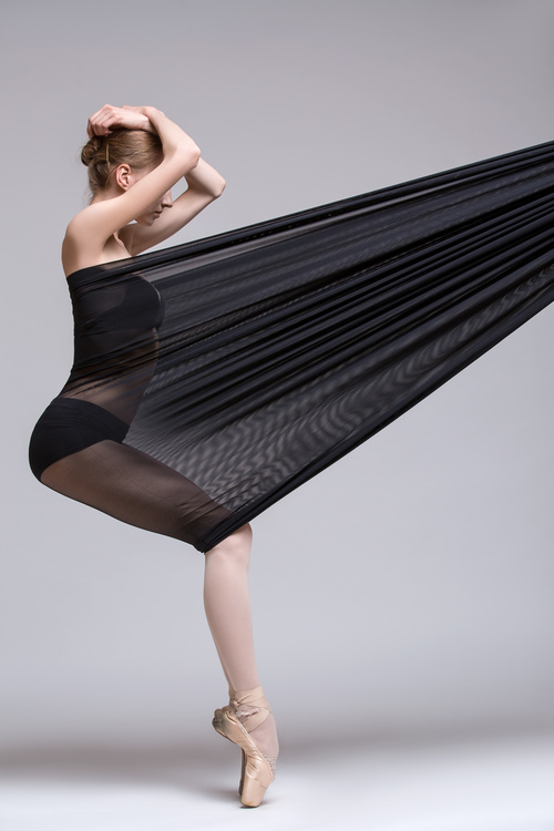 Slim dancer plays with black mesh fabric in the studio Stock Photo 05