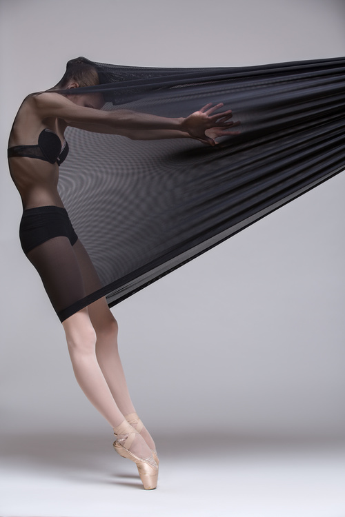 Slim dancer plays with black mesh fabric in the studio Stock Photo 06