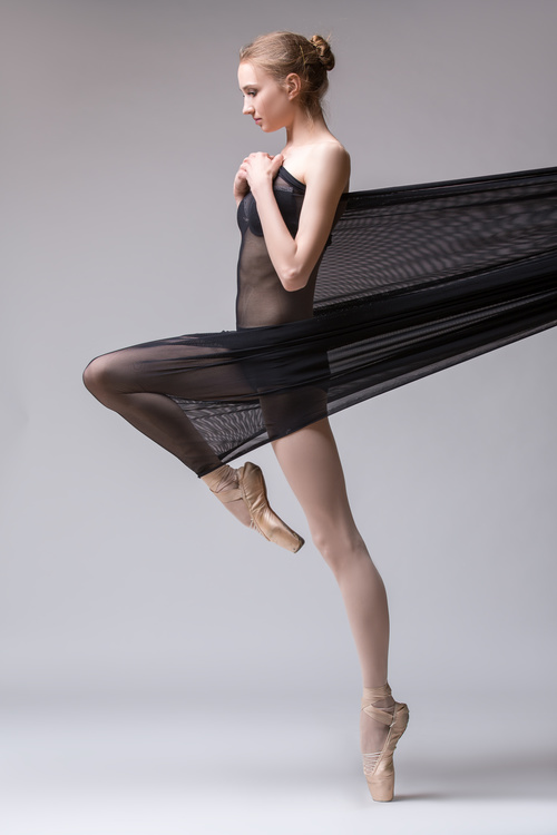 Slim dancer plays with black mesh fabric in the studio Stock Photo 09