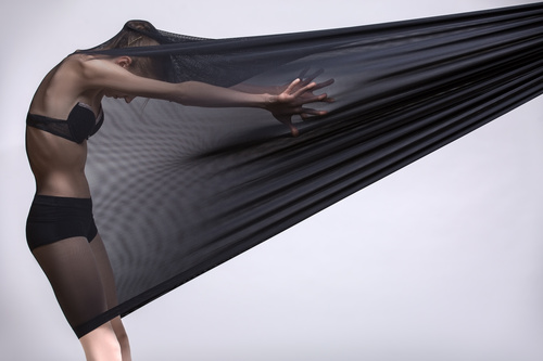 Slim dancer plays with black mesh fabric in the studio Stock Photo 10
