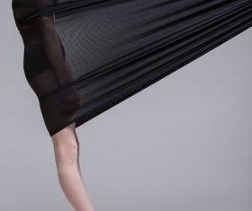 Slim dancer plays with black mesh fabric in the studio Stock Photo 11