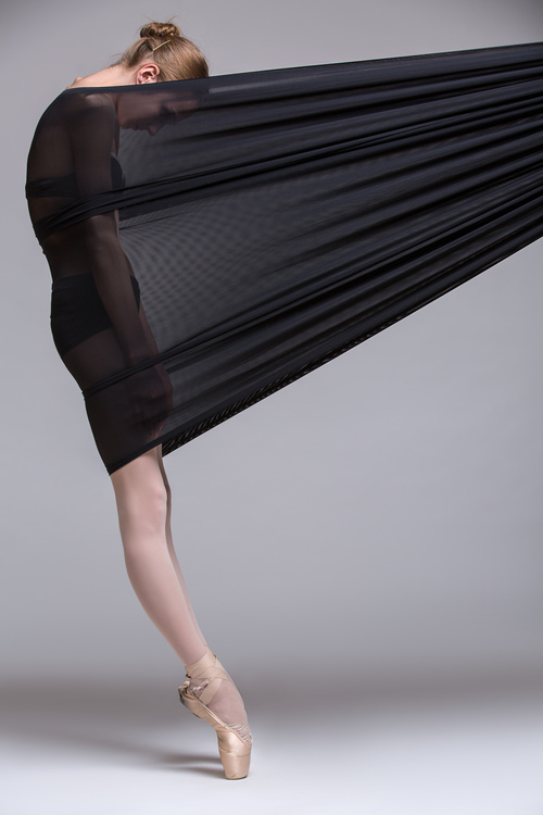 Slim dancer plays with black mesh fabric in the studio Stock Photo 11