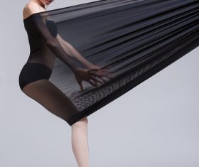 Slim dancer plays with black mesh fabric in the studio Stock Photo 13