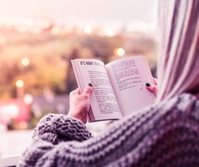 Young Woman Reading a Book on Terrace Stock Photo