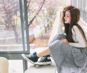 Asian girl sitting at the window with her eyes closed Stock Photo