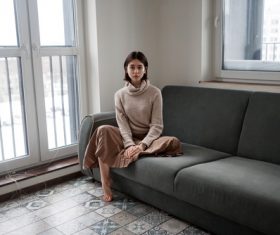 Barefoot woman sitting on sofa indoors Stock Photo