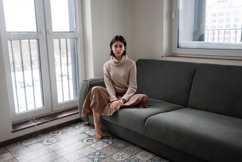 Barefoot woman sitting on sofa indoors Stock Photo