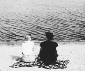 Black and white photography couple sitting on the beach Stock Photo