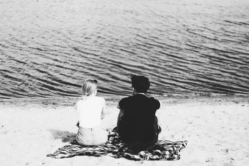 Black and white photography couple sitting on the beach Stock Photo
