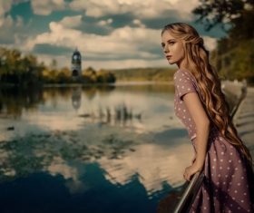 Blonde long hair women standing on the sidewalk by the river Stock Photo