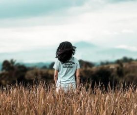 Child standing in the dry grass Stock Photo