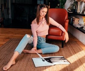 Girl sitting on the floor in the house and reading magazine Stock Photo