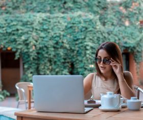 Girl wearing sunglasses in an outdoor cafe surfing the internet Stock Photo