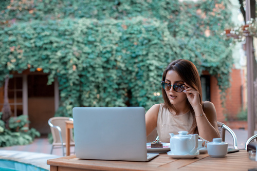 Girl wearing sunglasses in an outdoor cafe surfing the internet Stock Photo