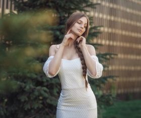 Pretty girl in white dress standing outdoors posing Stock Photo