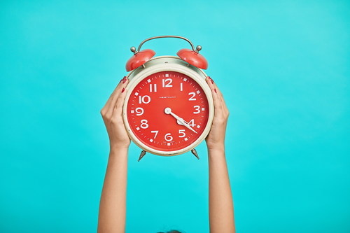 Small alarm clock in woman hands Stock Photo