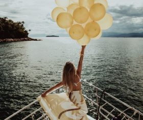 Stock Photo Woman standing on the yacht holding up balloons