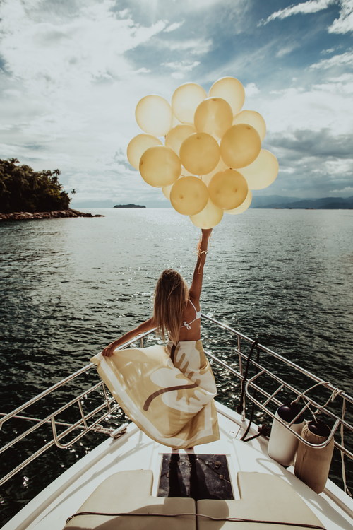 Stock Photo Woman standing on the yacht holding up balloons