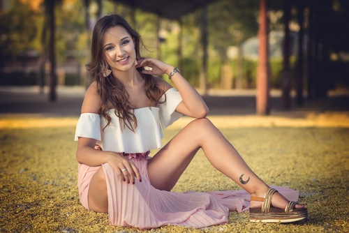 Stock Photo Woman with tattoo on leg sitting on the grass