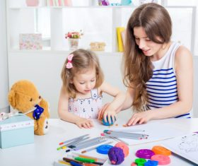 Stock Photo Young mother with her daughter playing with plasticine