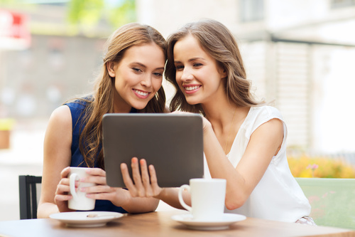 Two women drinking coffee watching videos Stock Photo