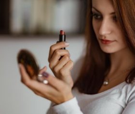 Woman holding small mirror and lipstick Stock Photo