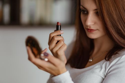 Woman holding small mirror and lipstick Stock Photo