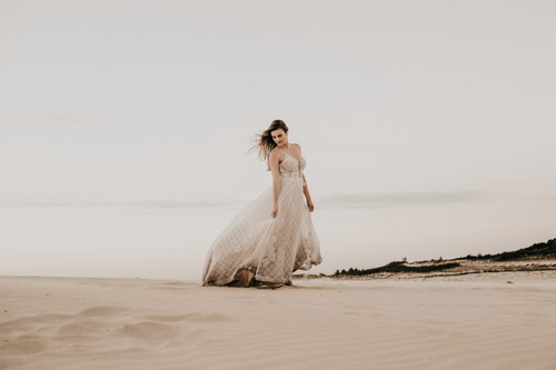 Woman in white dress walks on the beach Stock Photo