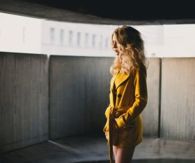Woman in yellow coat looks into the distance Stock Photo
