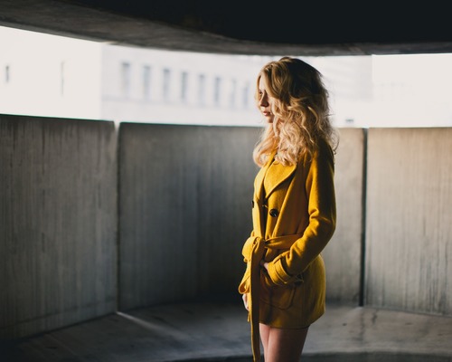 Woman in yellow coat looks into the distance Stock Photo