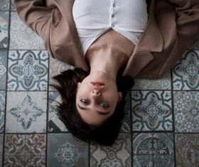 Woman lying on the floor indoors looking at the ceiling Stock Photo