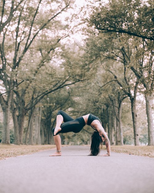 Woman practicing yoga on the tree-lined road Stock Photo