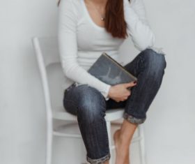 Woman sitting on chair holding book Stock Photo