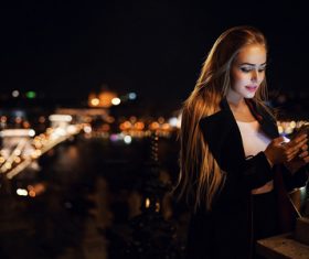 Woman using smartphone outdoors at night
