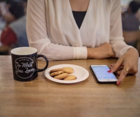 Woman using smartphone to browse information in cafe Stock Photo