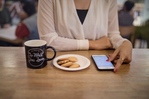 Woman using smartphone to browse information in cafe Stock Photo