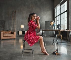 Woman wearing red floral dress doing pose on an indoor chair Stock Photo 01
