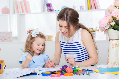 Young mother and daughter coloring picture book with colored pencils Stock Photo 03
