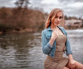 outdoors women wearing denim tight dress sitting by the river Stock Photo 02