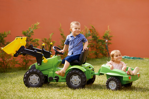 Brother driving toy car carrying sister Stock Photo