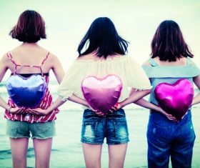 Girl holding heart shaped balloon behind her Stock Photo