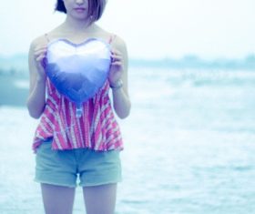 Girl holding heart shaped balloon by the sea Stock Photo