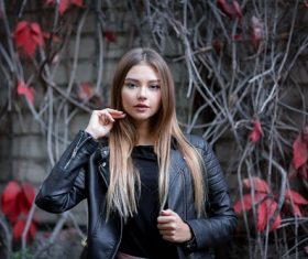 Girl in a leather jacket and red maple leaf behind her Stock Photo
